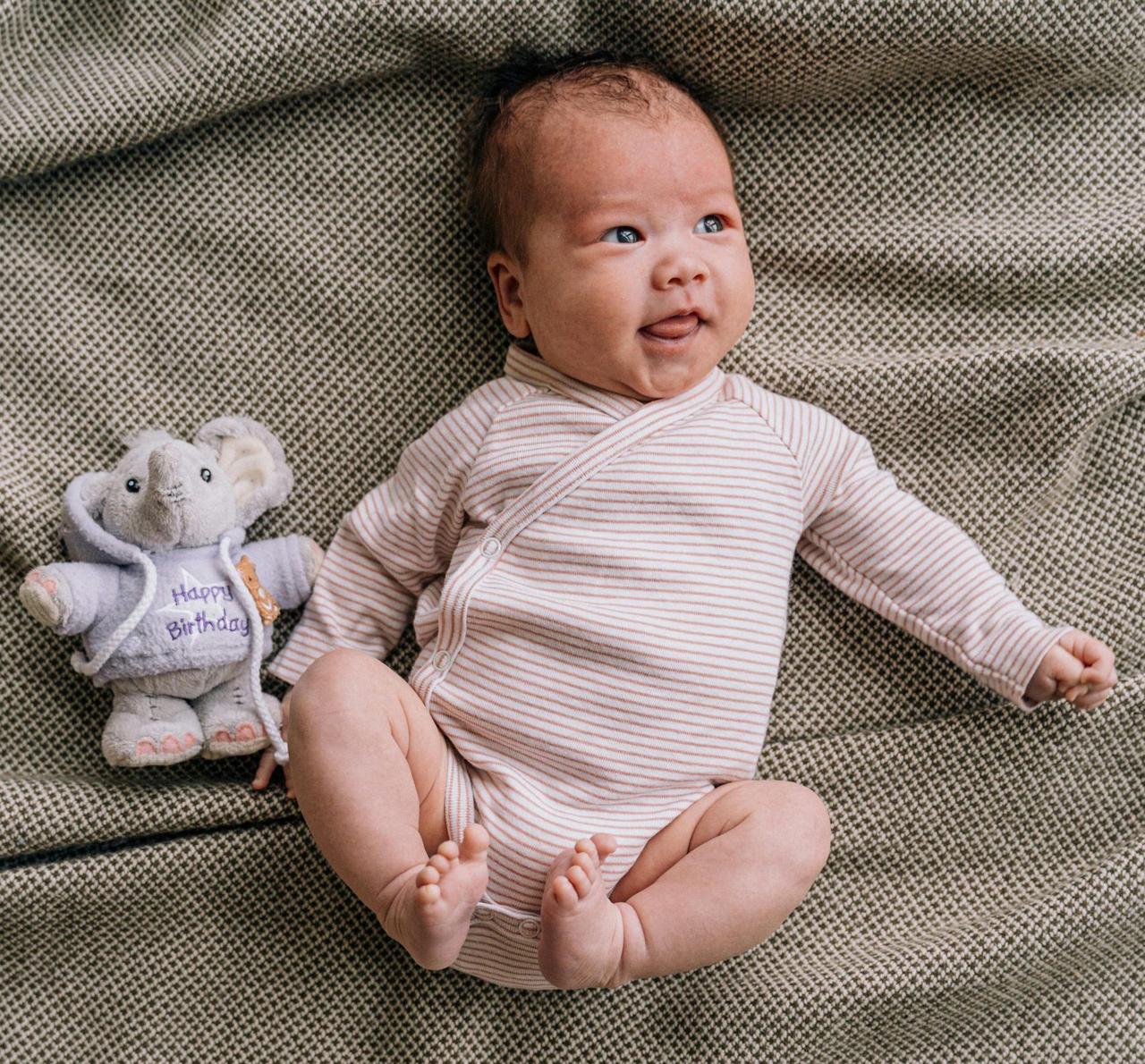 Baby in striped pink and white onesie lying on a blanket