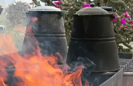 How to Make the Best Cup of Coffee A fire is burning in the background of two pots.