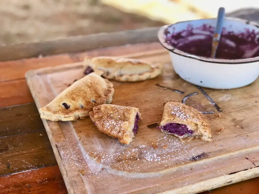 Purple-filled pastries on a wooden board.