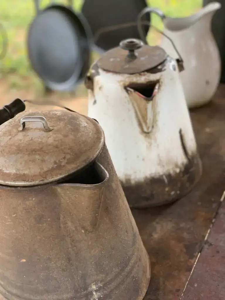 Three vintage metal pitchers on a table.