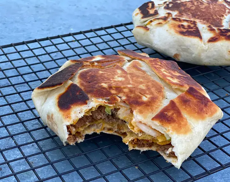 A close up of an open burrito on a grill