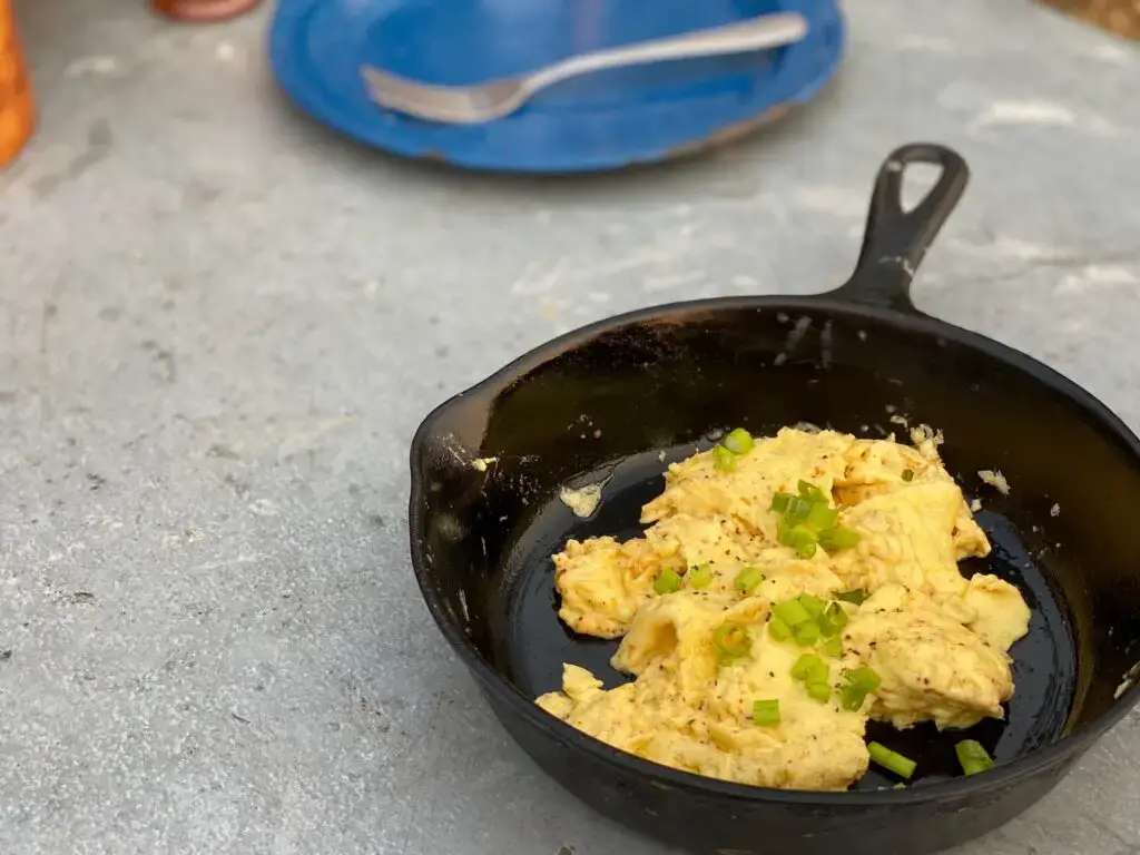 A pan of scrambled eggs with green onions.