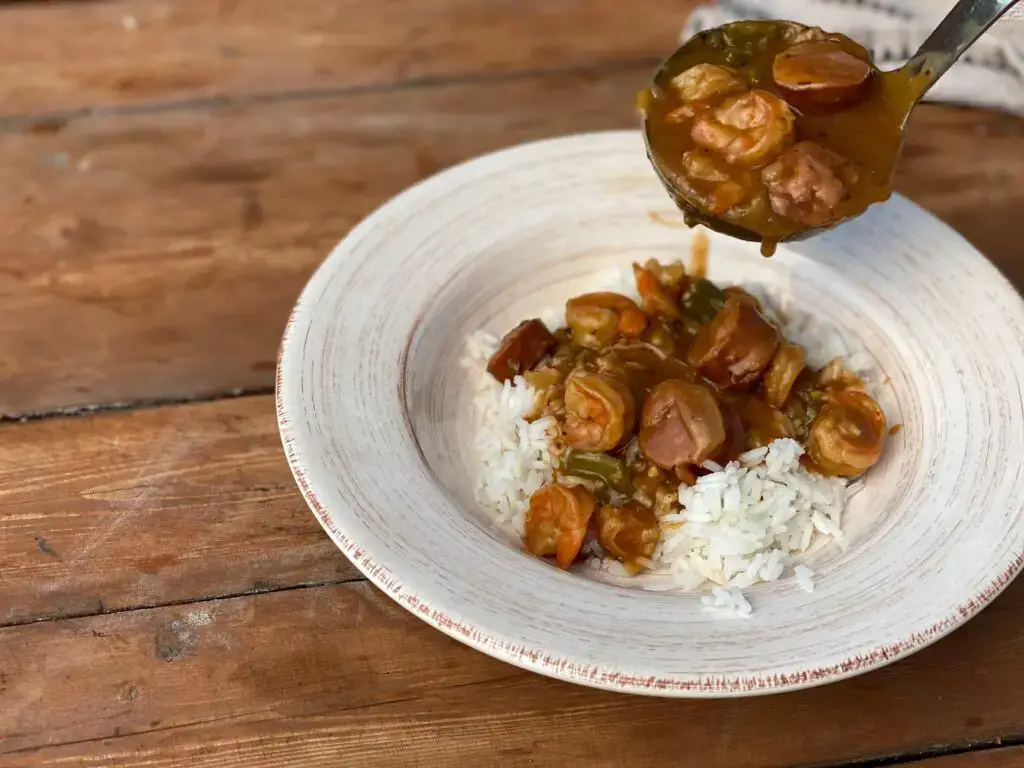 A bowl of rice and stew with sauce on top.