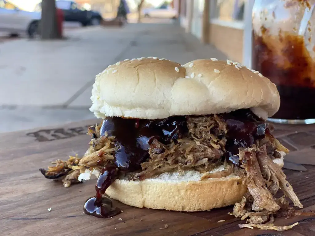 A sandwich with pulled pork and barbecue sauce.