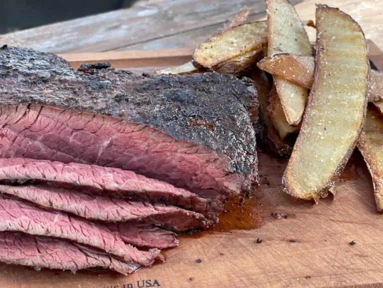 A close up of some meat and fries on a cutting board