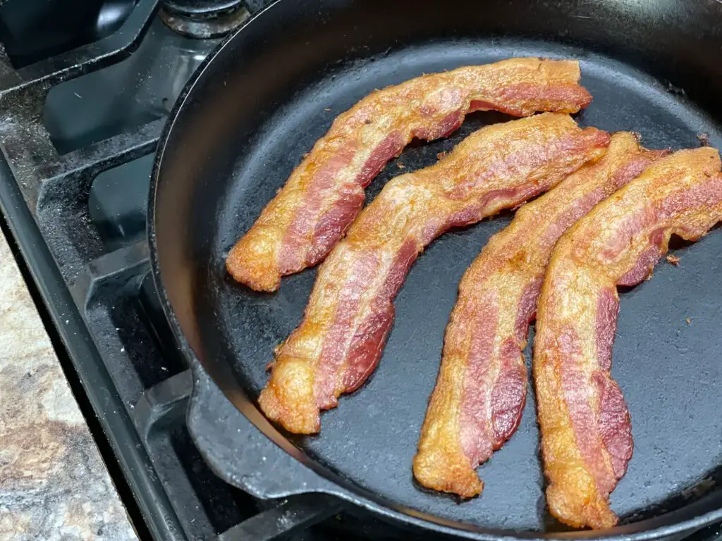 A pan with bacon in it on top of the stove.