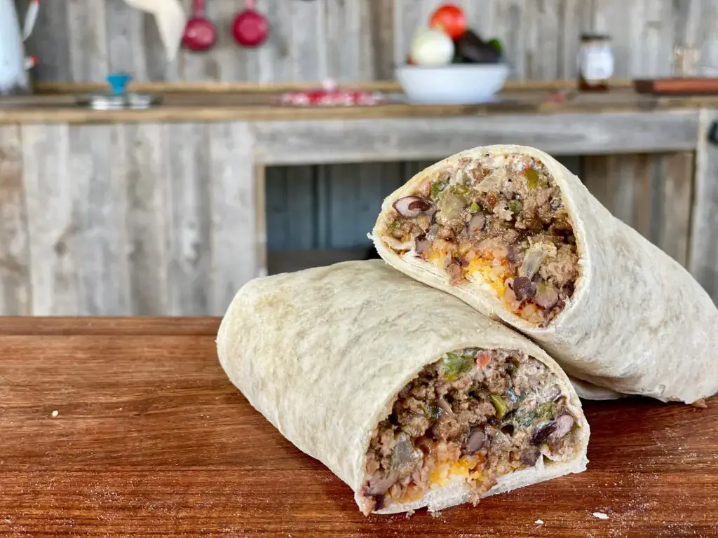 A burrito with meat and cheese on top of it.