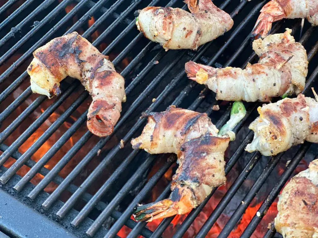 Bacon-wrapped shrimp grilling on a grill.