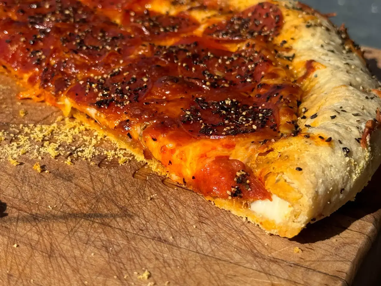 A piece of pizza sitting on top of a wooden board.