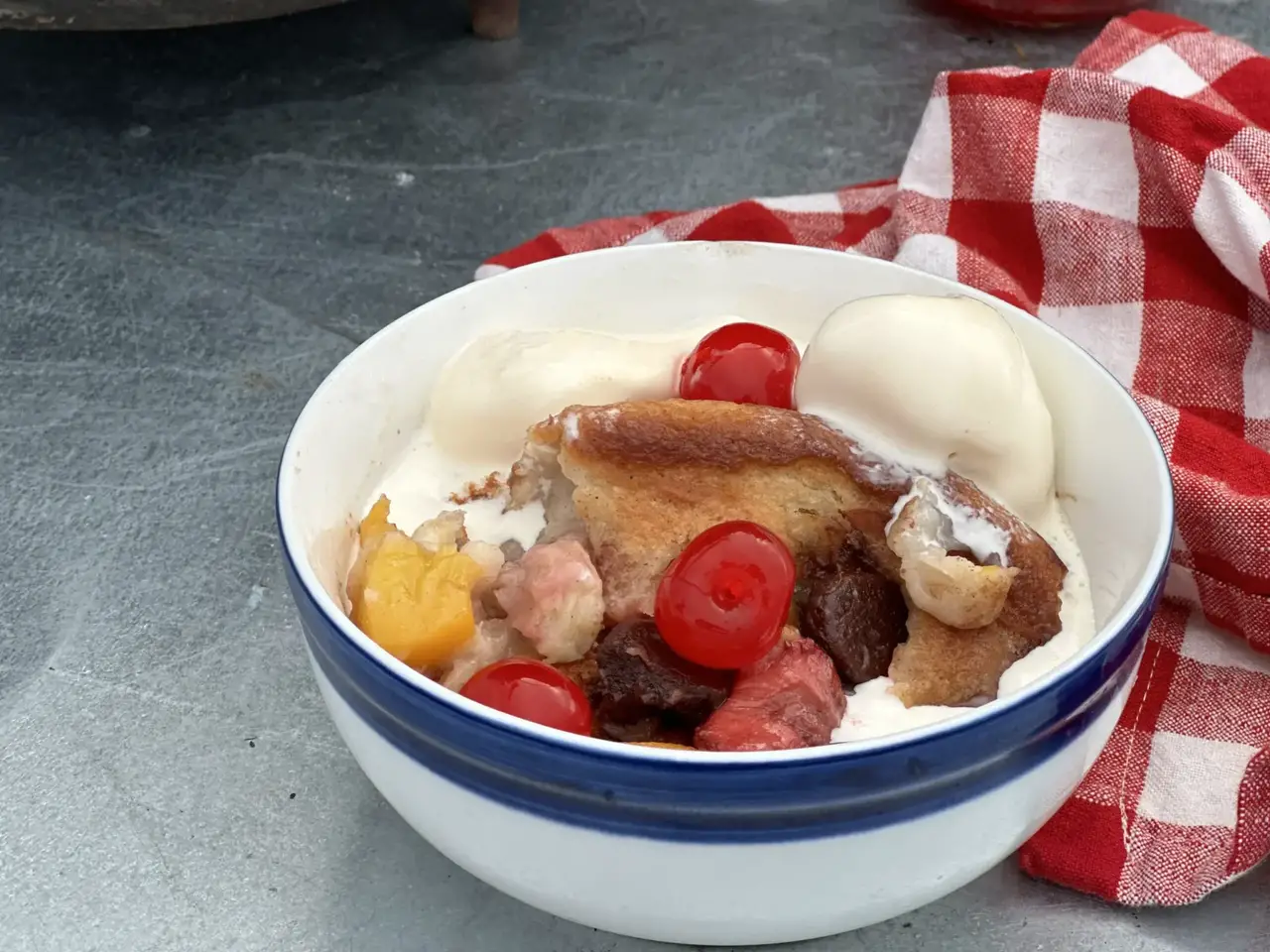 A bowl of fruit and ice cream on the table.