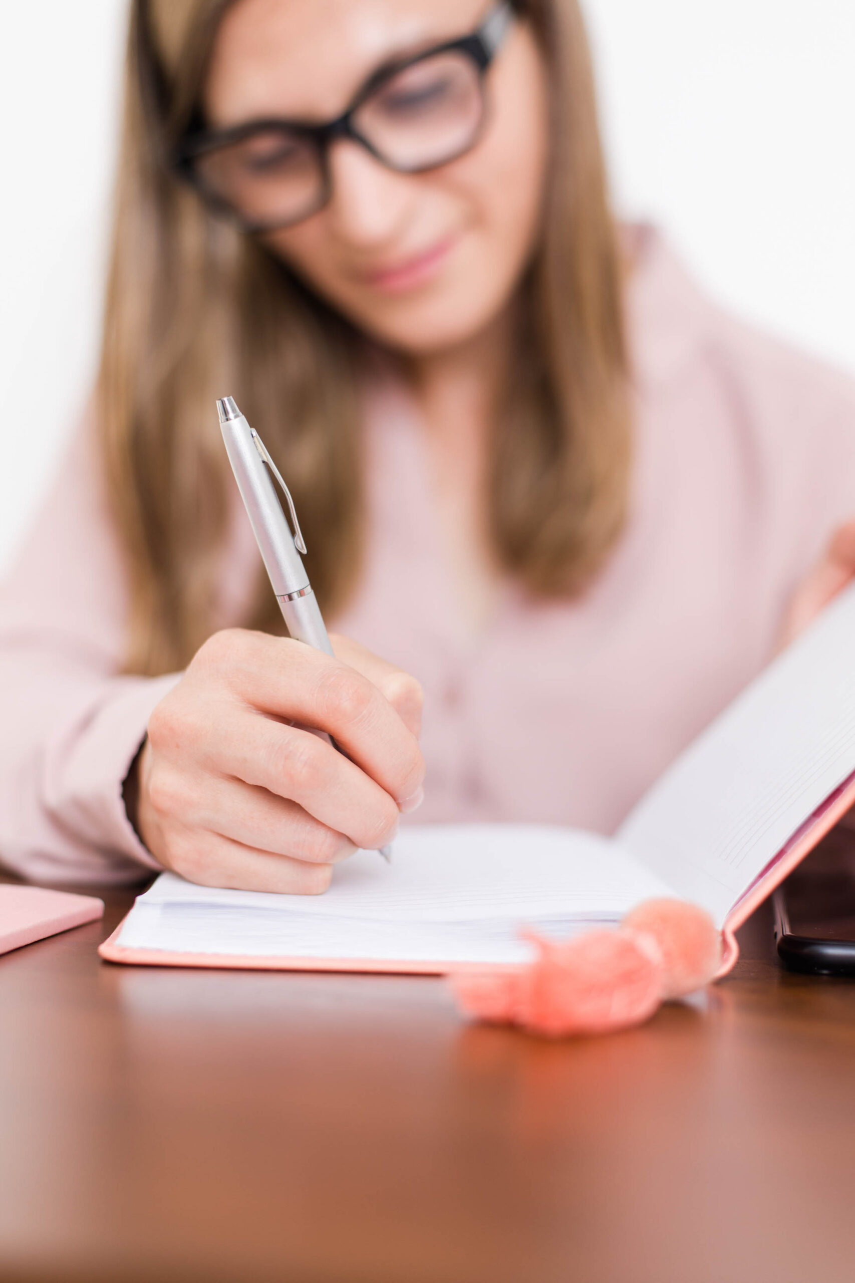 woman with glasses writing in journal