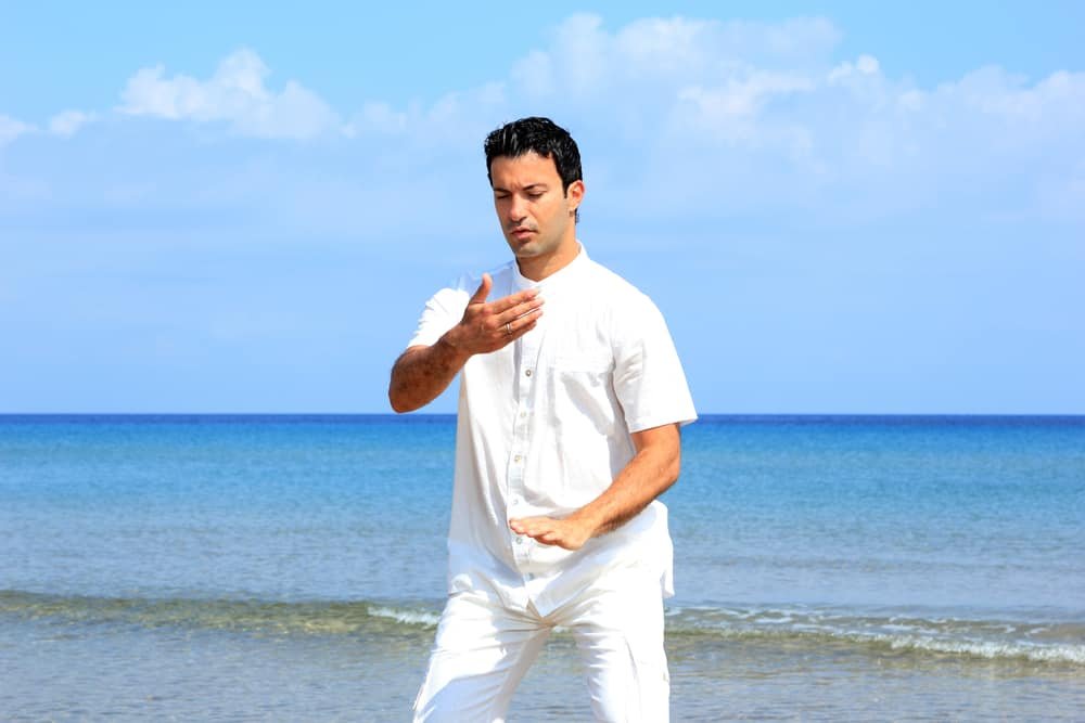 man on the beach meditating Tai chi